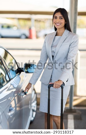 happy indian businesswoman opens car door at parking lot
