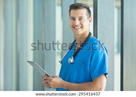 good looking male nurse holding tablet computer at workplace
