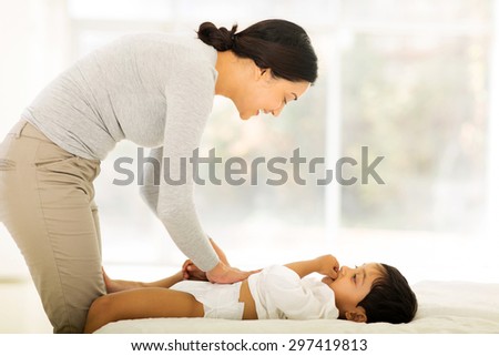 happy indian mother changing baby nappy