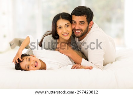 adorable little indian boy lying on bed with his parents