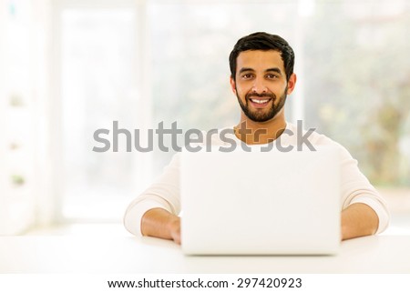 happy young indian man relaxing at home with laptop