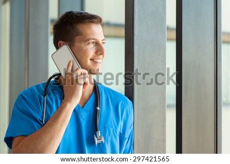 cheerful male nurse talking on mobile phone in clinic