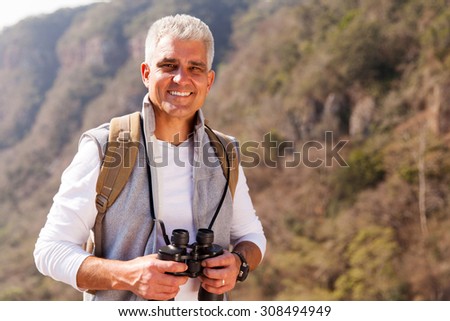 happy mid age man on top of the mountain with binoculars