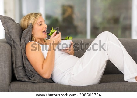 relaxed pregnant woman eating green salad at home