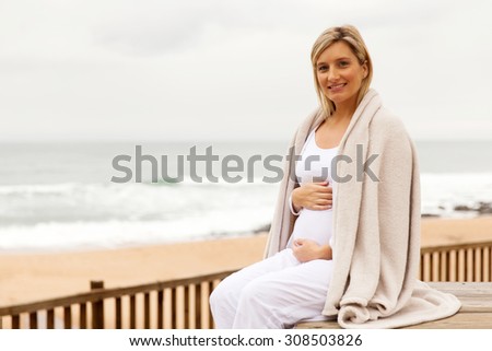 happy pregnant woman wrapped in blanket outdoors