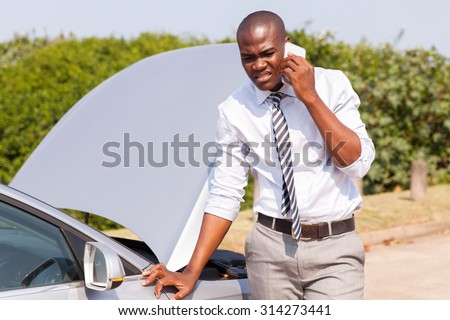 young African man calling for assistance with his car broken down by the roadside