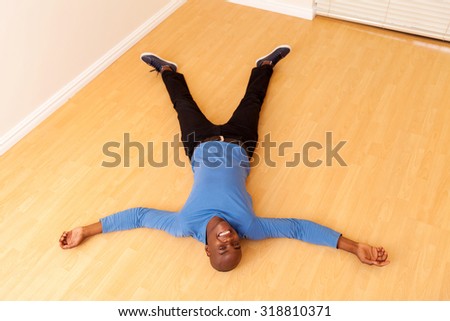 overhead view of young african man lying on the floor in his new home