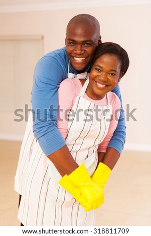 portrait of young african husband and wife embracing in their home