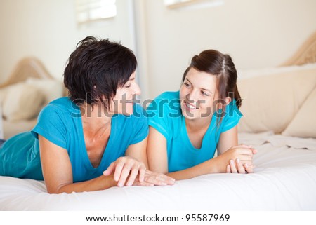 middle aged mother and teen daughter chatting on bed