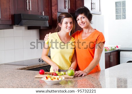 mother and teen daughter making fruit salad in kitchen