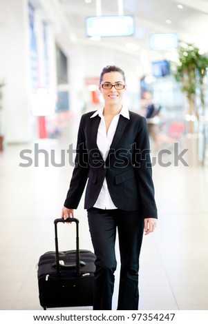 young beautiful businesswoman walking in airport with luggage