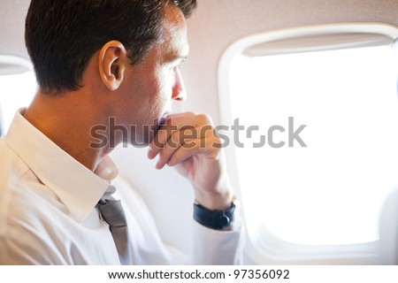 thoughtful businessman on airplane looking outside