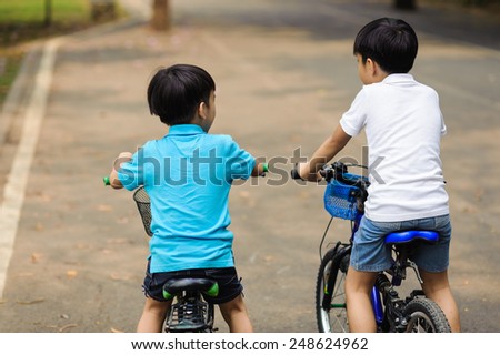 Older boy train the younger to bike
