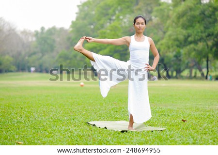 Beautiful woman practicing yoga in the park. Extended Hand To Big Toe Pose/Utthita Hasta Padangustasana.