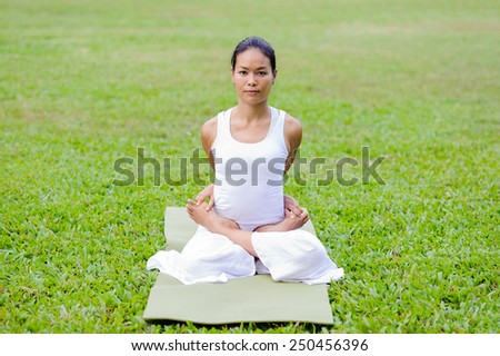 Beautiful woman practicing yoga in the park.The Locked Lotus Pose / Baddha Padmasana.