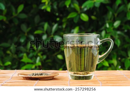 Hot herb tea in transparent glass on grass mat