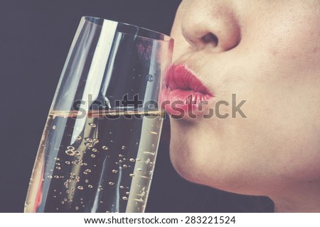 Vintage tone Close up focus on red lip Asian young woman kiss champagne on black background