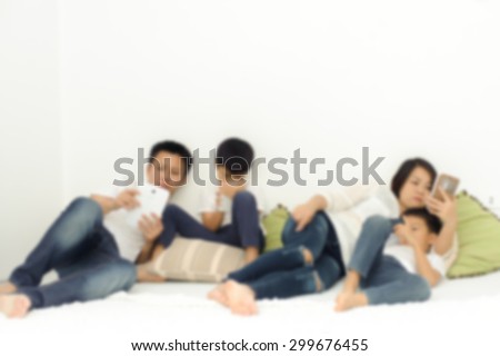 Out focus. Family in living room using smartphone and tablet device each one separately. Social network concept.