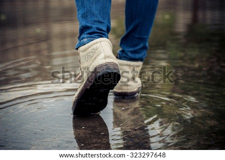 Dark color tone. Traveller female shoe walk on water on concrete floor after heavy raining.
