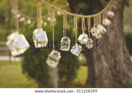 Decoration jars hanging from trees in a park.