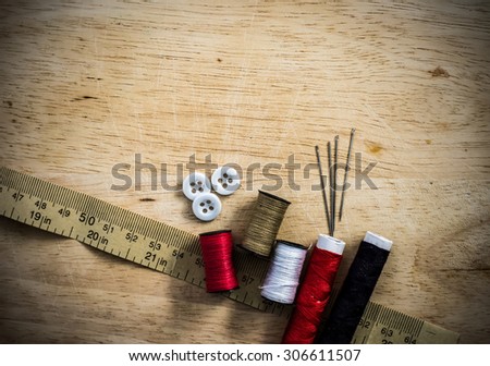 Sewing tools and colored tape/Sewing kit with thread and needles on the wooden background tools and colored tape/Sewing kit with thread and needles on the wooden background