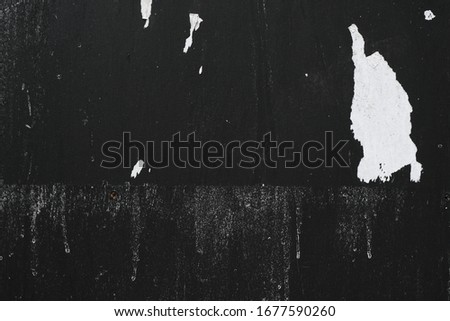 Black painted urban wall with bits of torn tattered white street posters ストックフォト © 