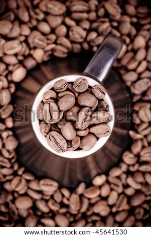 Coffee beans placed on top of a brown coffee mug or cup with a white outline.