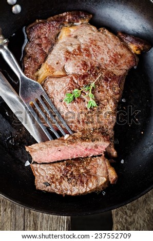 Roasted beef steak antrecot in iron pot on wooden background. Slice of steak