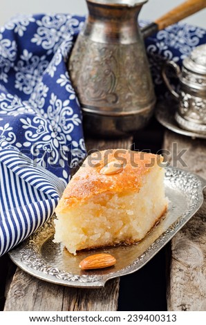 Basbousa (namoora) - arabian semolina cake with almond and honey syrup in iron vintage tray on wooden background. Slice of cake