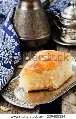 Basbousa (namoora) - arabian semolina cake with almond and honey syrup in iron vintage tray on wooden background. Slice of cake