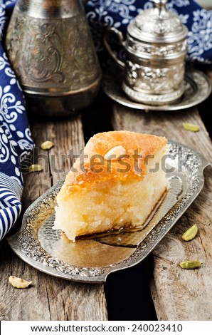 Basbousa (namoora) - arabian semolina cake with almond and honey syrup in iron vintage try on wooden background. Slice of cake