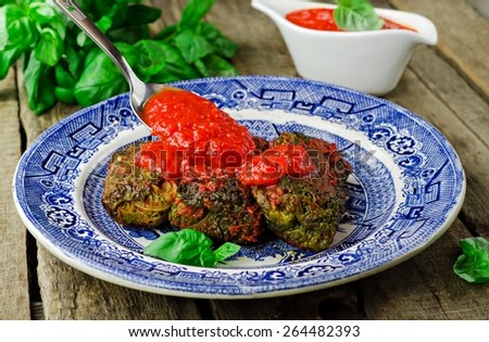 Verzini al forno - stuffed roll Savoy cabbage with tomato sauce and basil in vintage plate on wooden  background