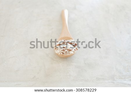 Rice grain in the wood spoon put on concrete table with color and selected focus