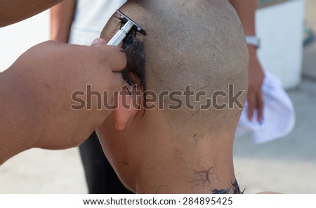 Samut Prakan -Thailand-May-24- : Thai man gets his head shaved by a monk with intend during a Buddhist ordination ceremony on May 24, 2015 in Samut Prakan, Thailand.
