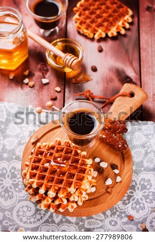 Fresh thick belgium waffles with honey and coffee on a wooden background. Selective focus