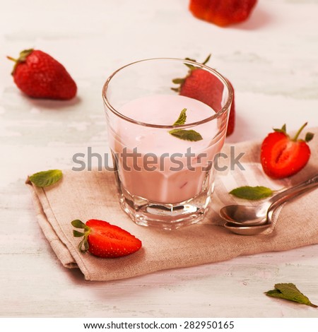 Homemade yoghurt with fresh strawberry and mint on white wooden background. Selective focus. Toned square image