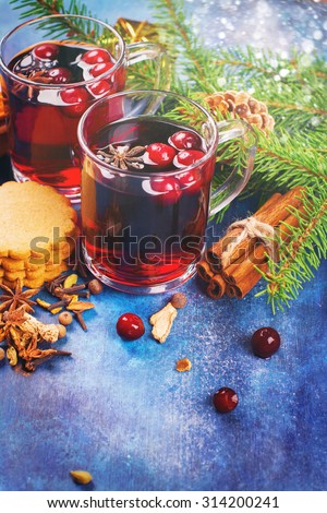 Hot xmas punch with spices and cranberry in glass cups. Xmas or new year concept. Xmas decorations, wooden background. Selective focus. Toned image