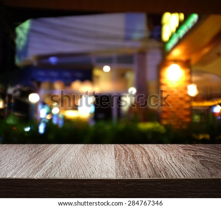 Empty wooden deck table with blur shot night restaurant