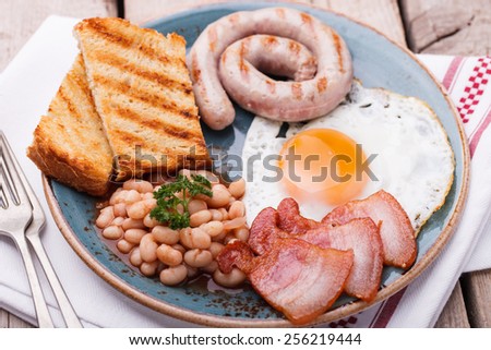 English breakfast with fried eggs, bacon, sausages, beans, toasts and fresh juice.selective focus
