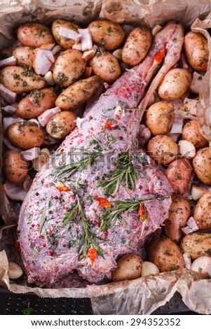 Raw lamb leg marinated with spices, garlic and rosemary, with a young potato.selective focus
