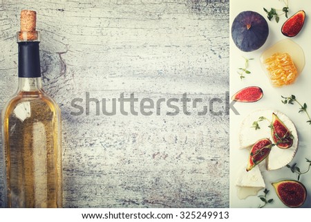 Cheese Board,appetizer.Brie cheese,bottle of white wine,figs,honey and thyme and white wine.Copy space.Toned image. Vintage style.selective focus