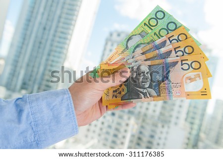 Human hand with Australian money with business building