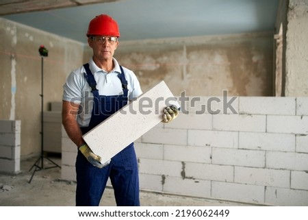 Similar – Foto Bild Arbeiter baut Mauer mit roten Blöcken und Mörtel