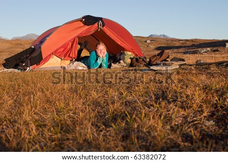 female hiker in a tent in the evening light