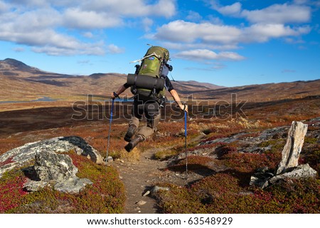 jumping long distance hiker with backpack in Lapland