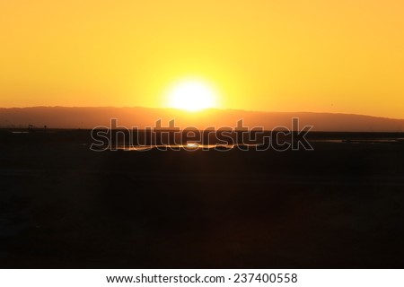 Sun peaking over hills at sunset