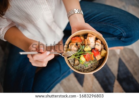 Girl holds a paper plate with healthy food sitting on the floor. Home delivery food. Healthy eating concept. When you stay at home. Foto stock © 