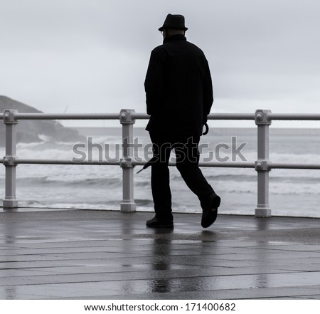 old man walking with umbrella