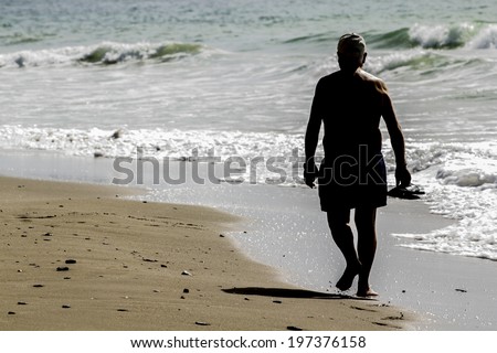 old man walking along the beach shore