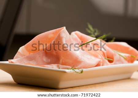 photo of thin slices of italian mortadella called also bologna on small rectangular plate served as appetizer